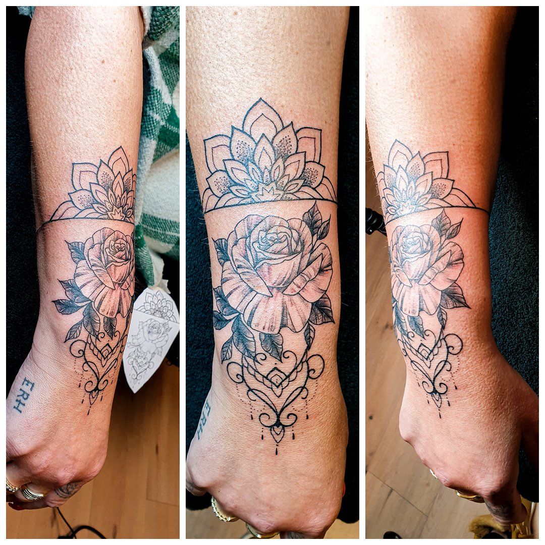 Een vrouw heeft een tatoeage van een roos en een lotusbloem op haar pols.