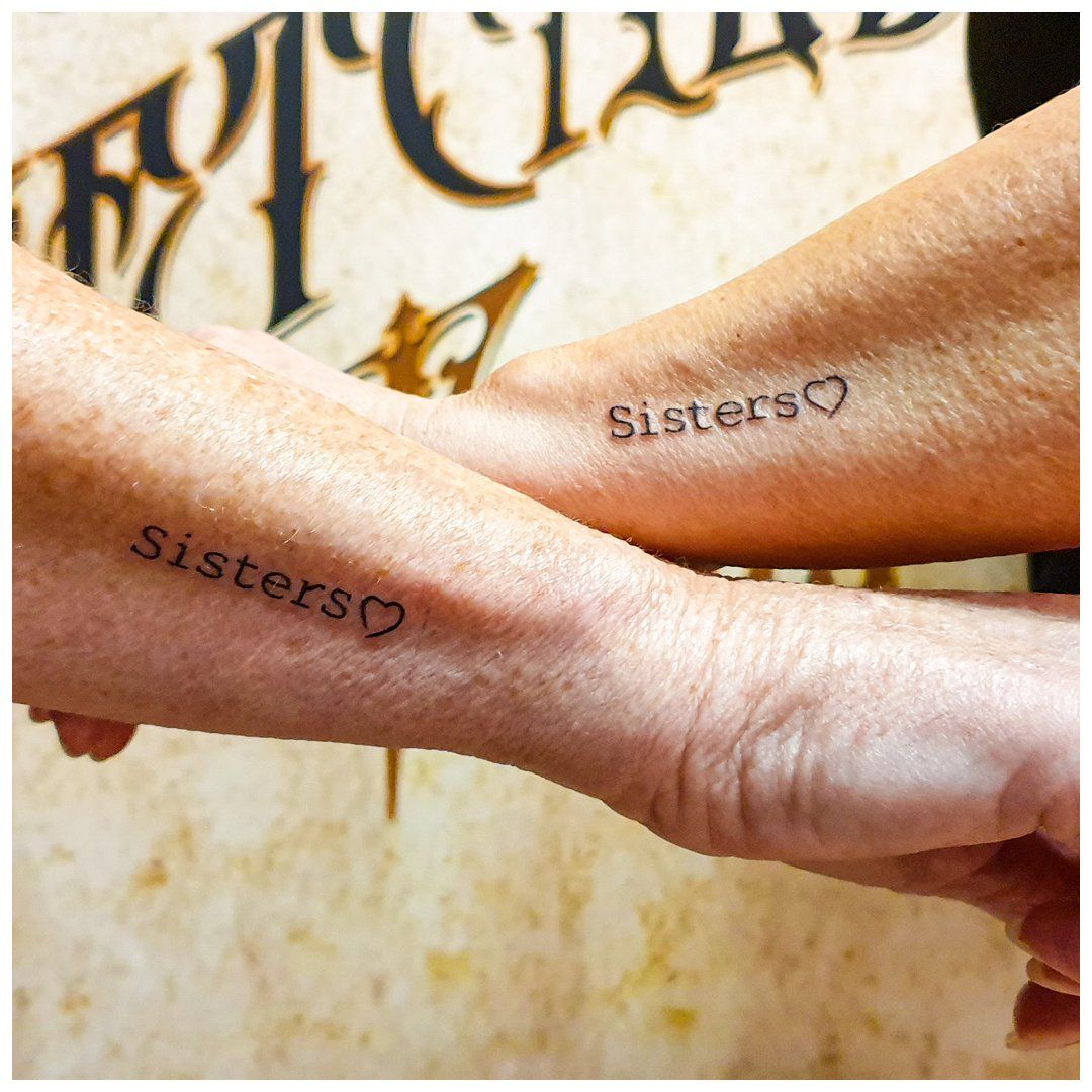 Twee vrouwen hebben bijpassende tatoeages van zussen op hun polsen