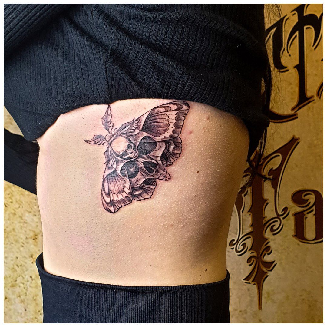 Een vrouw heeft een tatoeage van een mot op haar zij