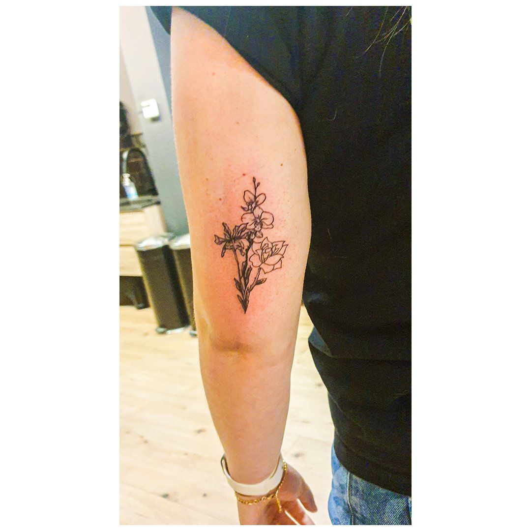 Een vrouw heeft een tatoeage van een kruis met bloemen op haar arm.