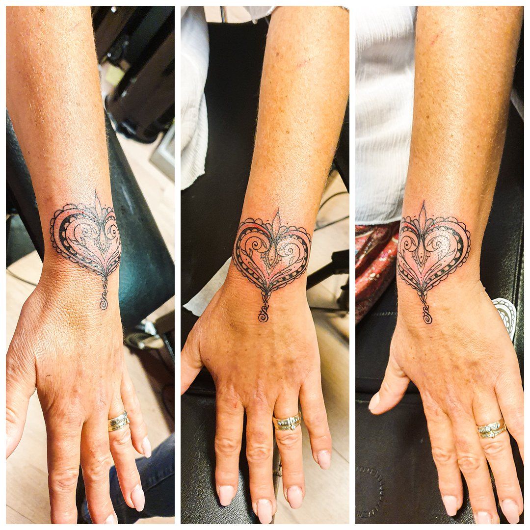 Een vrouw heeft een hart-tatoeage op haar pols.