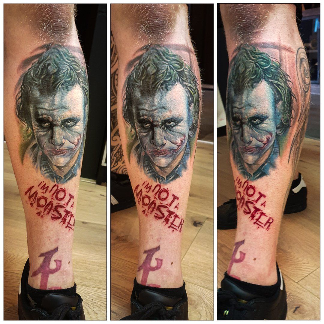 Een man heeft een tatoeage van de joker op zijn been.