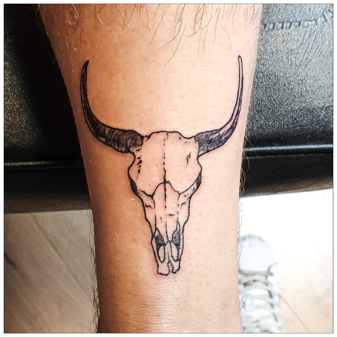 Een man heeft een tatoeage van een stierenschedel op zijn been