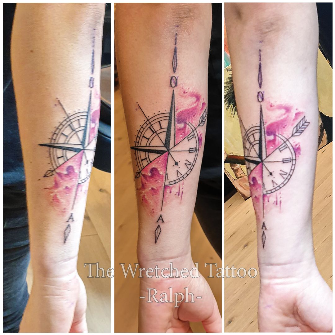 Een persoon heeft een tatoeage van een kompas op zijn onderarm