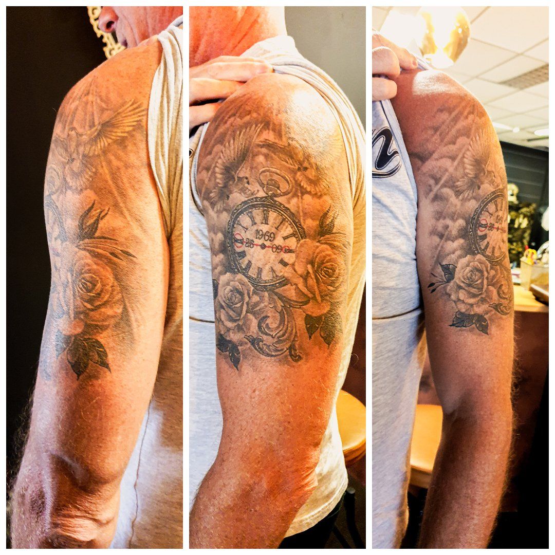 Een man heeft een tatoeage van een klok en rozen op zijn arm