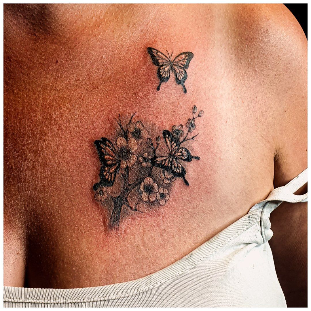 Een vrouw heeft een tatoeage van vlinders en bloemen op haar borst.