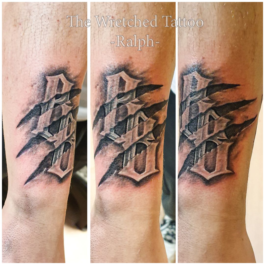 Een tatoeage op de arm van een man waarop de gestikte tatoeage staat