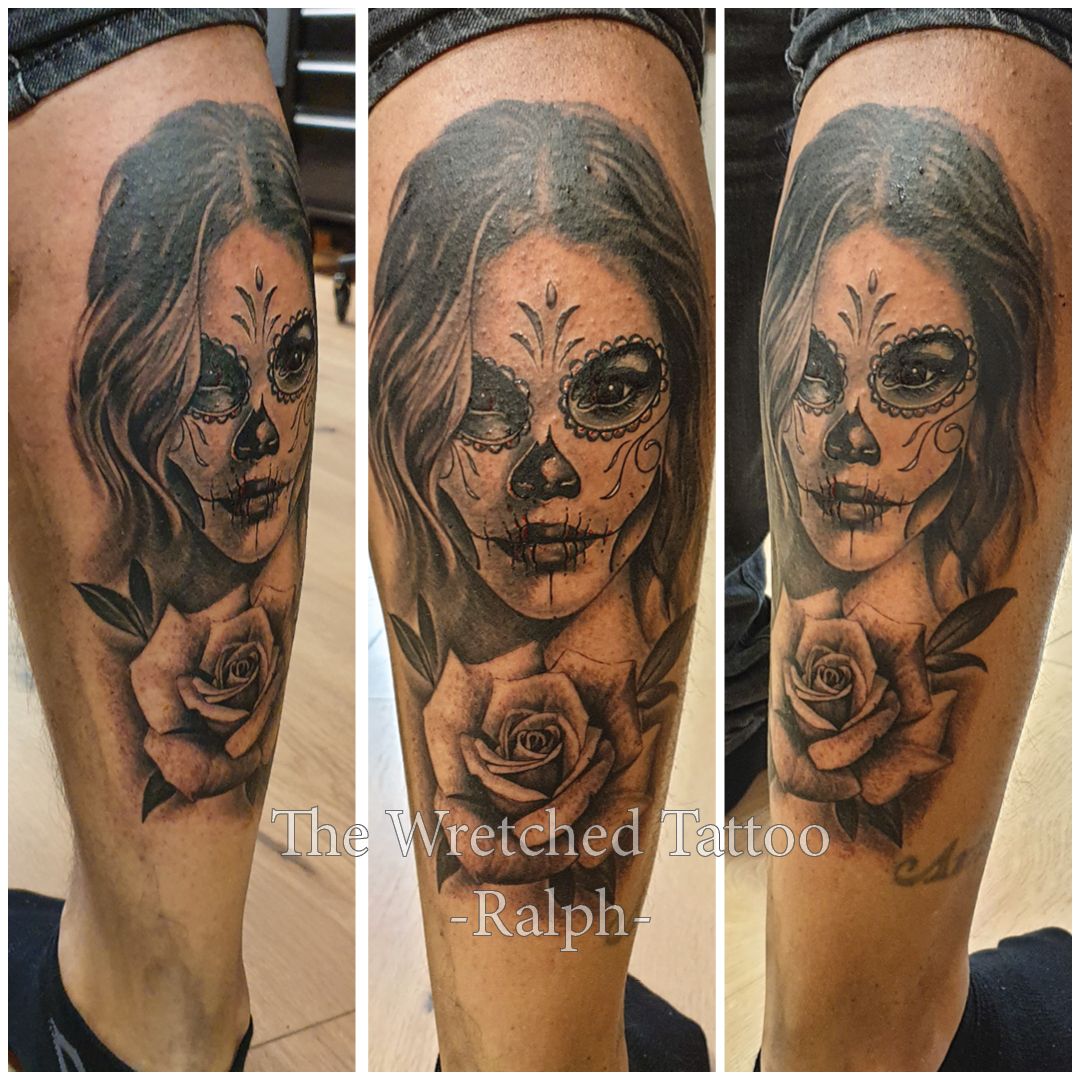 Een zwart-witte tatoeage van een vrouw met rozen op haar been