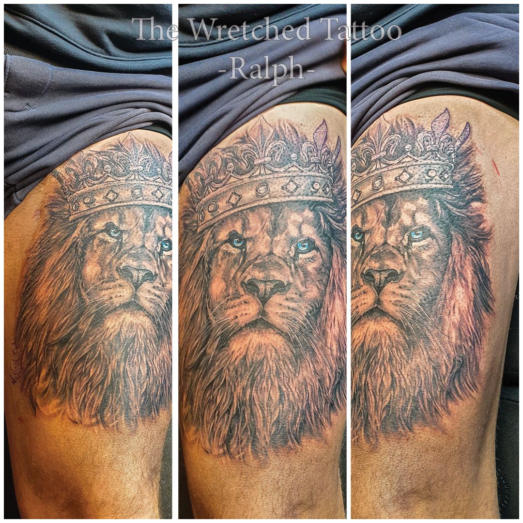 Een man heeft een tatoeage van een leeuw met een kroon op zijn dij.
