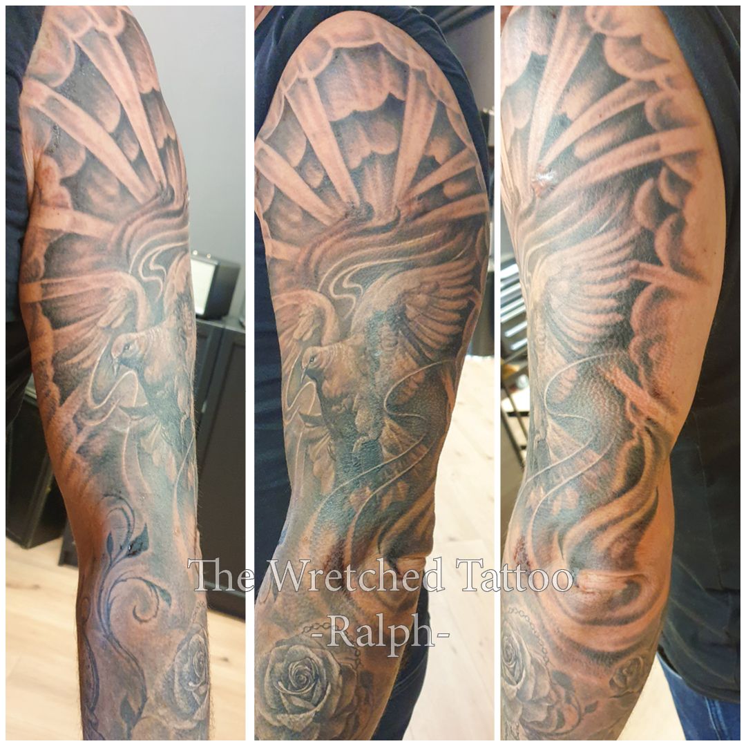 Een man heeft een tatoeage op zijn arm van een duif die vliegt met zonnen stralen