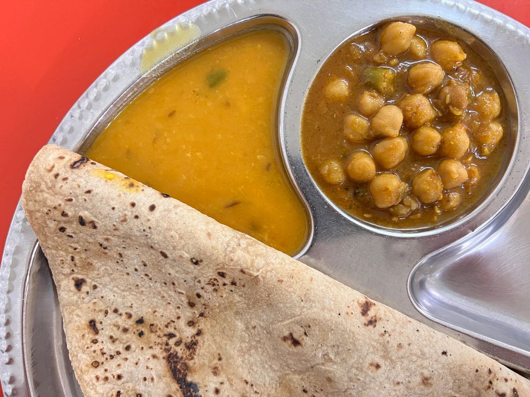 Indian thali with dal, chickpeas, and roti on a silver plate.