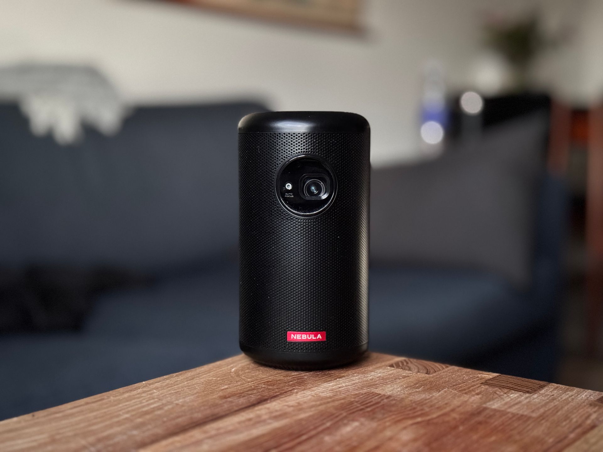 Black cylindrical Nebula projector on a ledge with a red logo.
