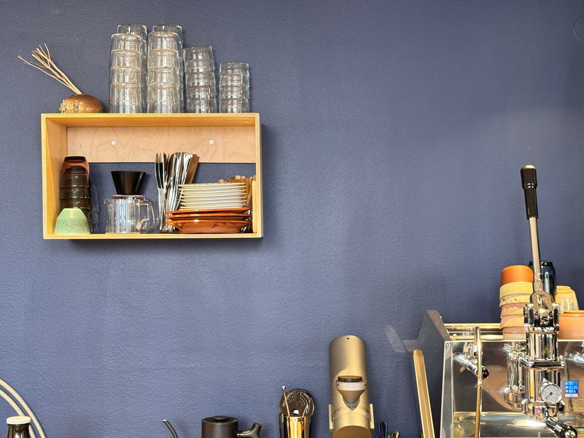 Coffee, glass carafe, and small glass on wooden tray, set on cobblestone.