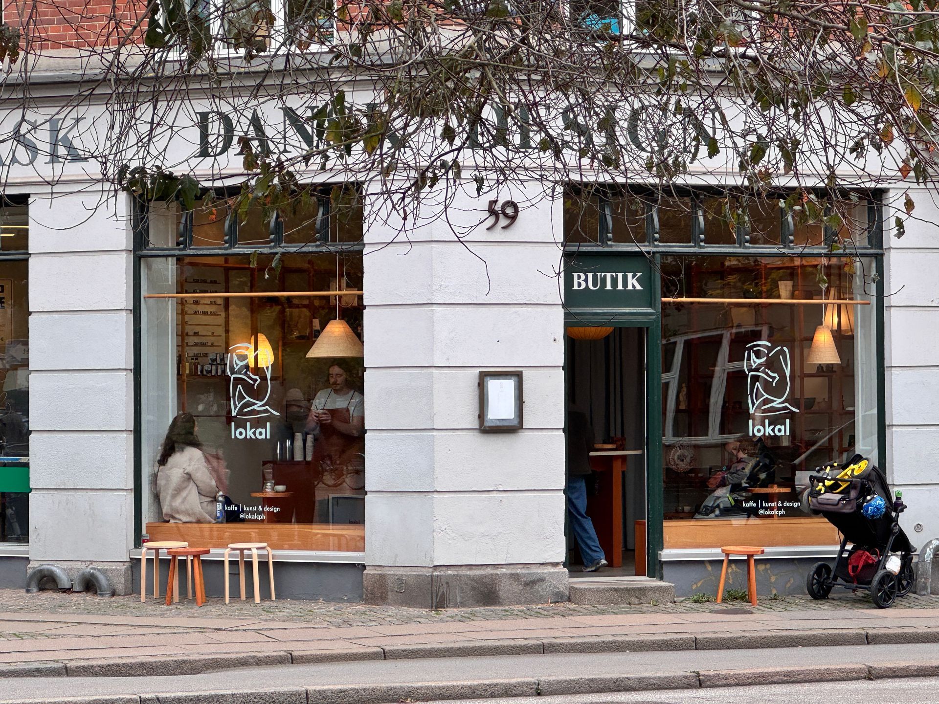 Danish design shop with large windows; people seated inside, a stroller outside the door.