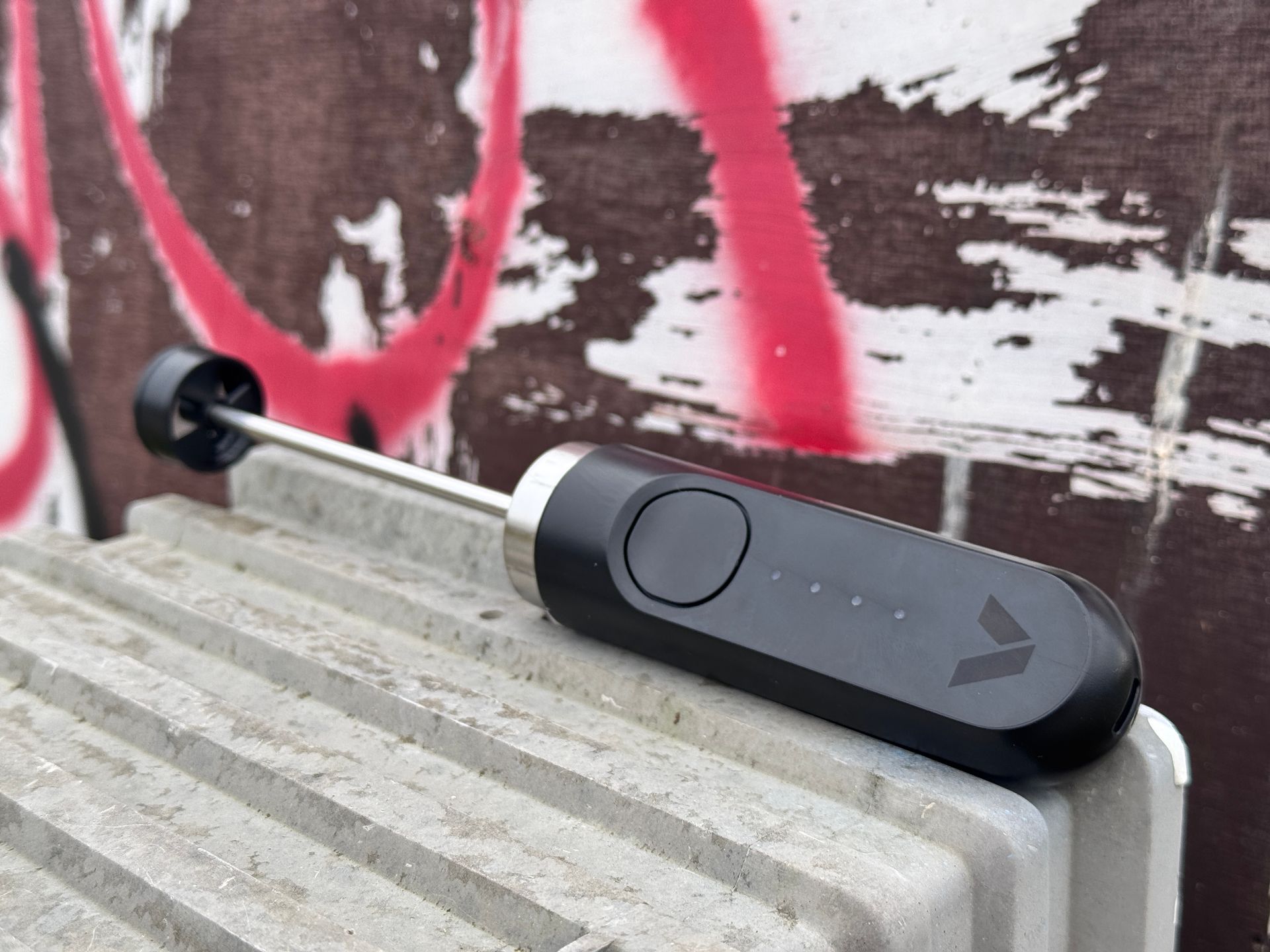 Black wind meter on concrete block, with a graffiti-covered wall backdrop.