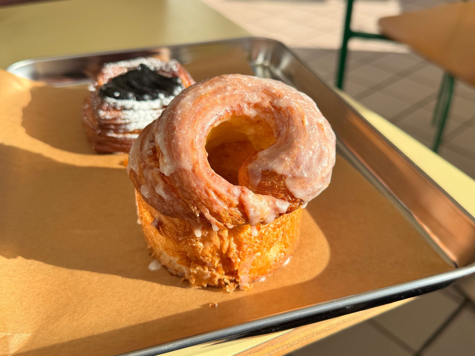 Coffee, glass carafe, and small glass on wooden tray, set on cobblestone.