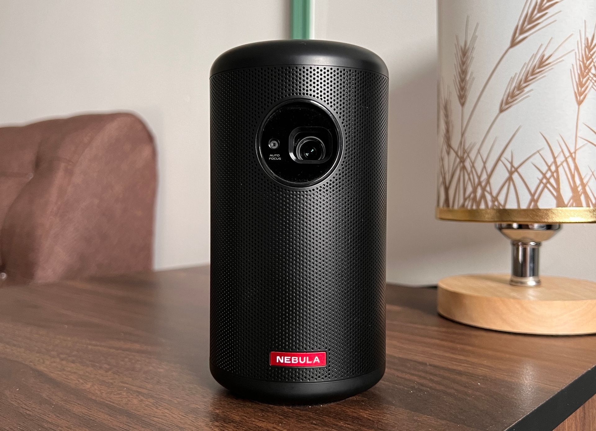 Black cylindrical Nebula projector on a ledge with a red logo.