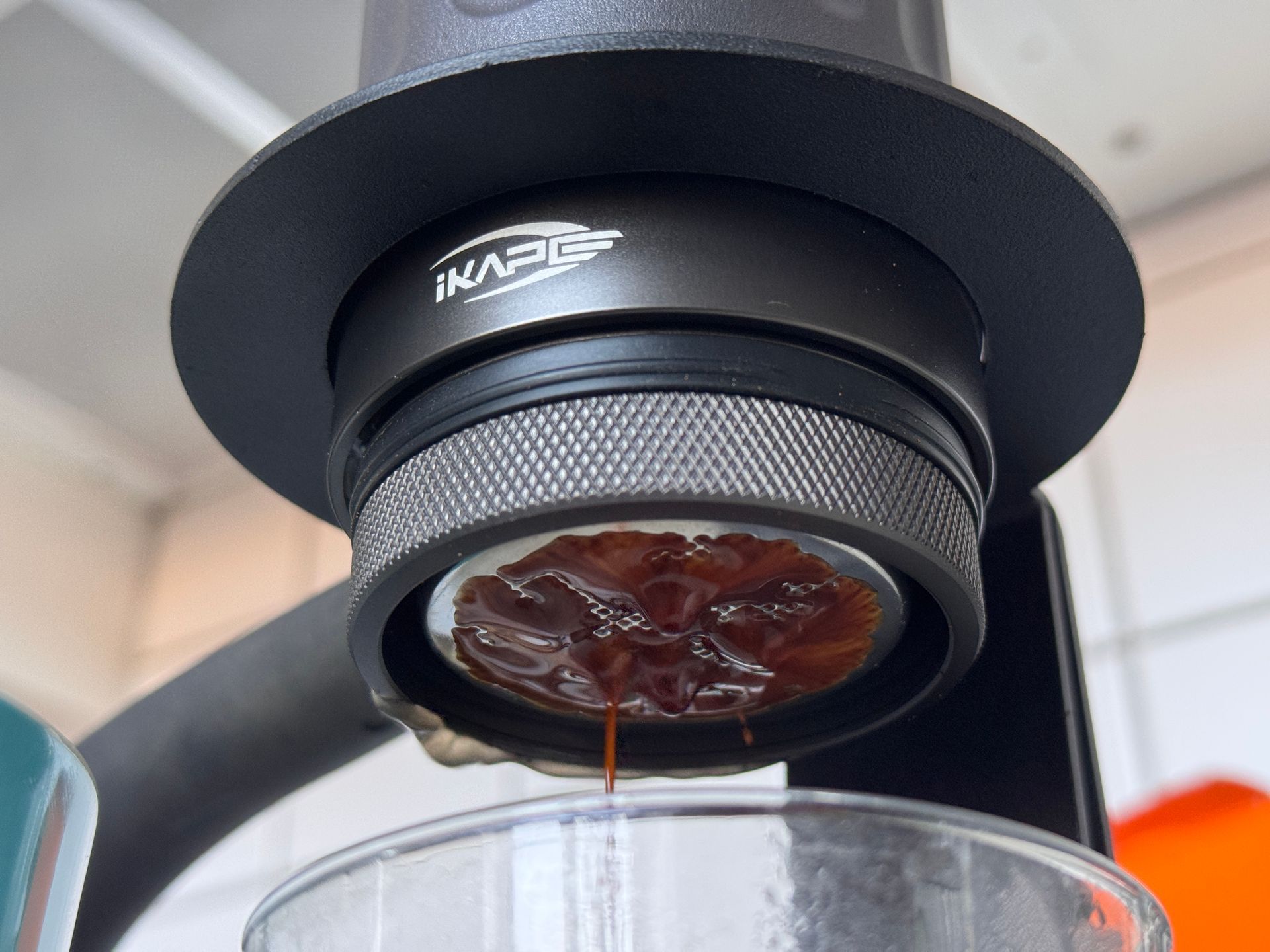 Black espresso maker and accessories in an open travel case on a wooden surface.