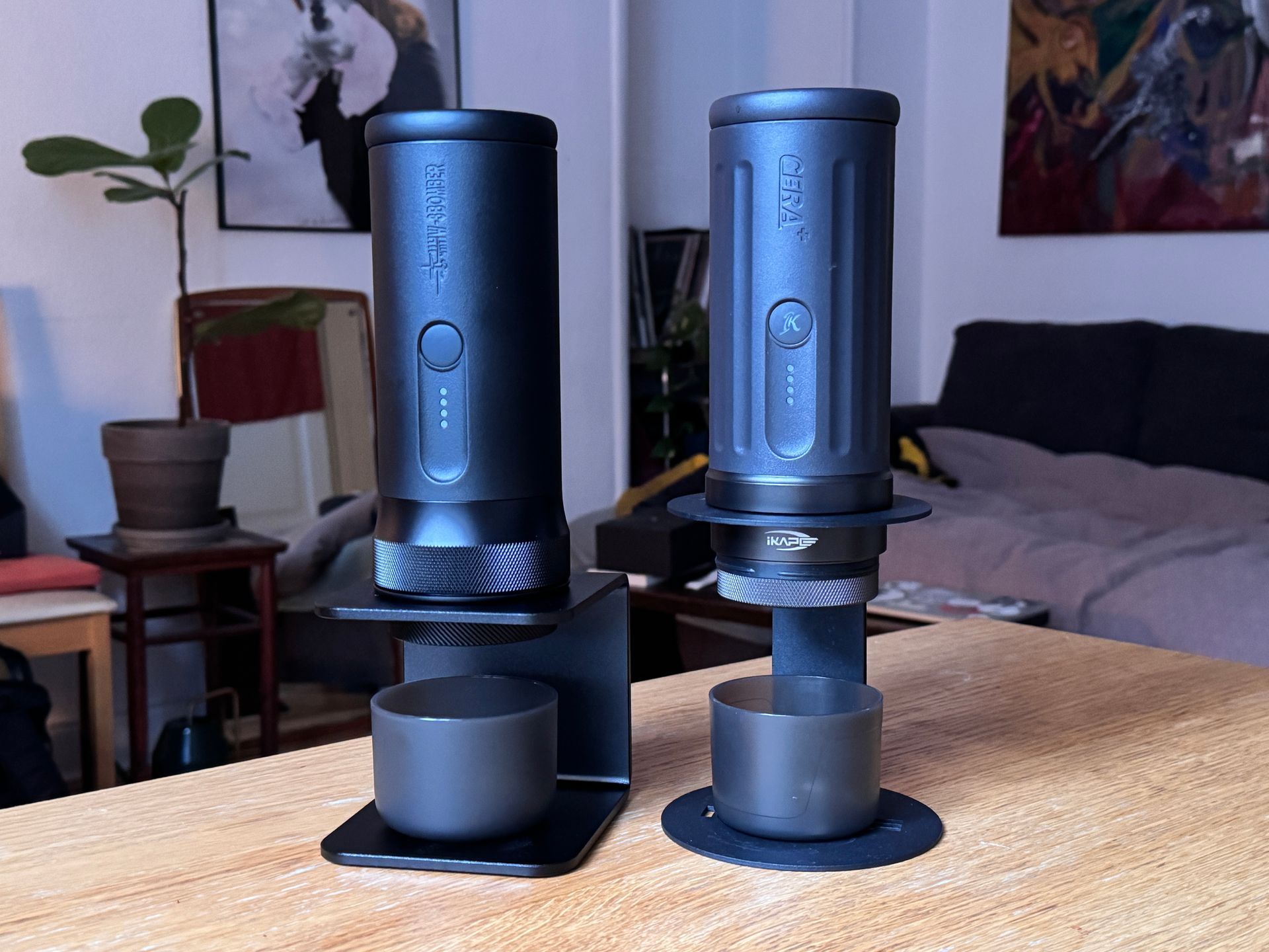 Four black coffee grinders of different designs on a counter, with a green container on the left.