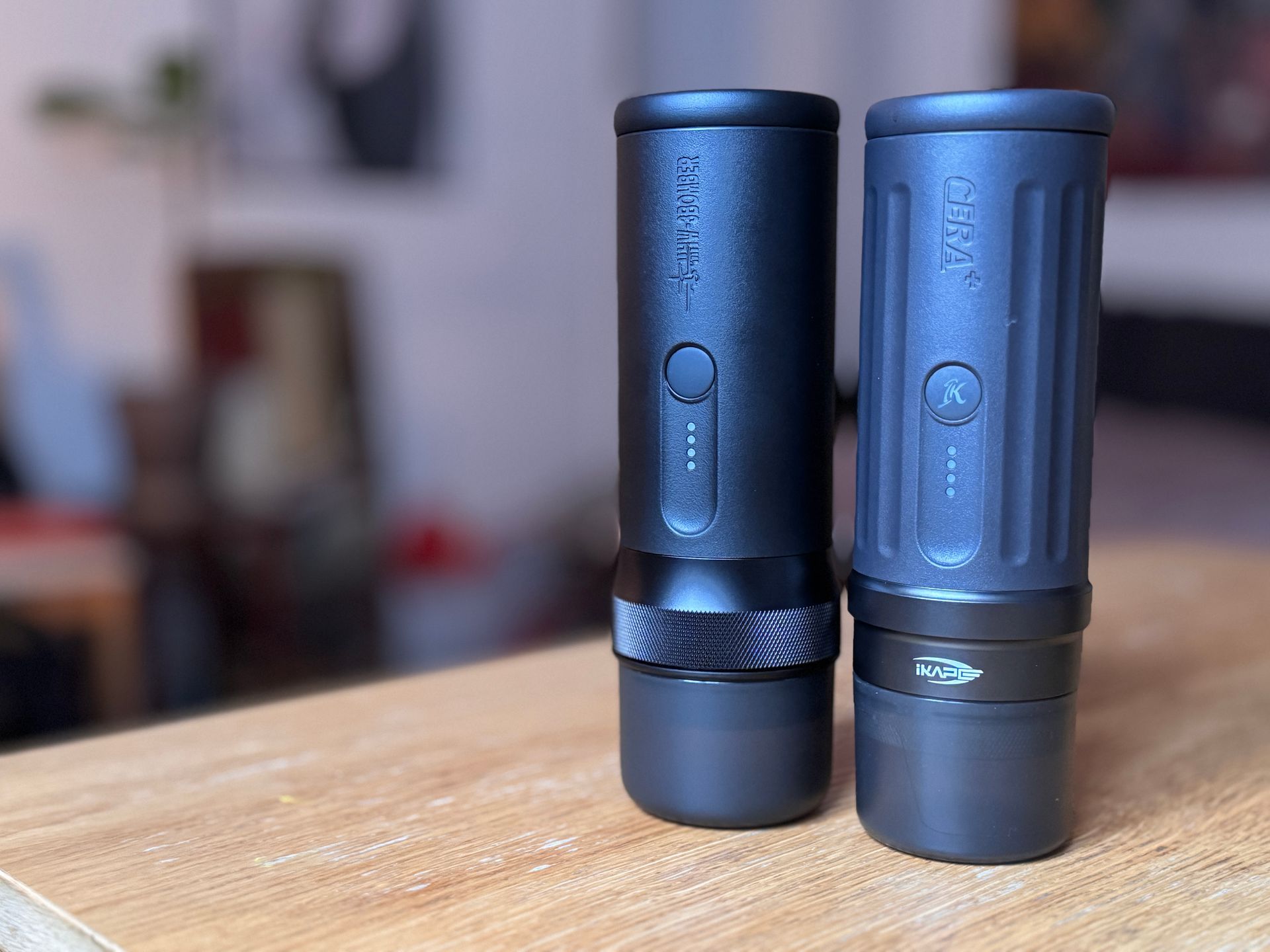Four black coffee grinders of different designs on a counter, with a green container on the left.