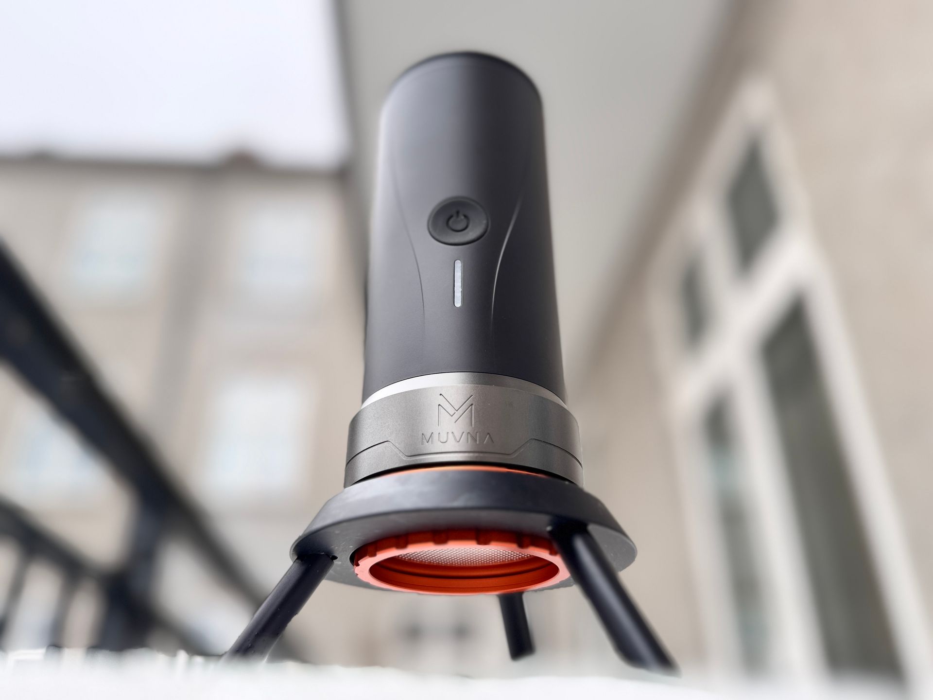 Four black coffee grinders of different designs on a counter, with a green container on the left.