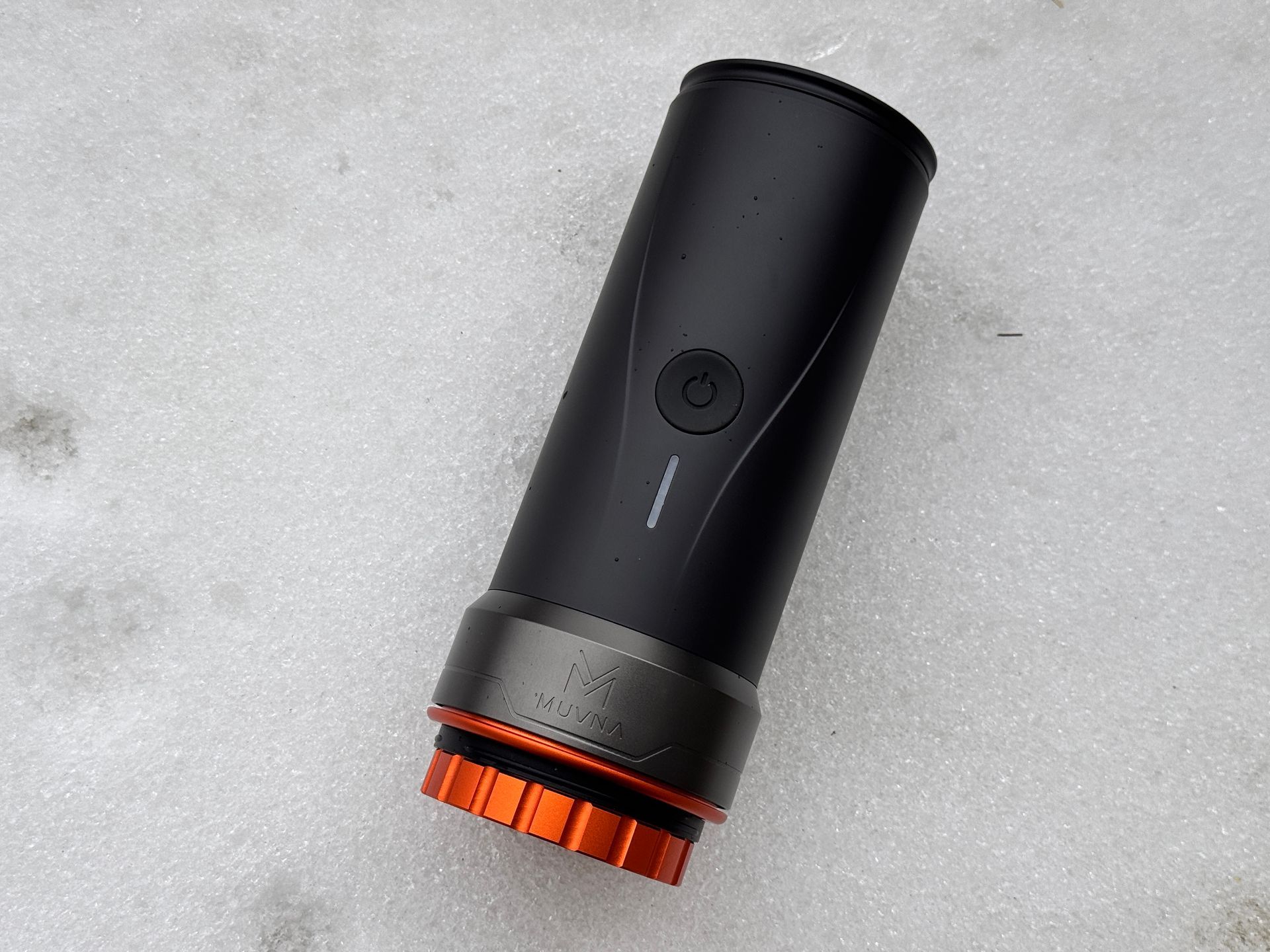 Black and orange portable espresso maker on snow.