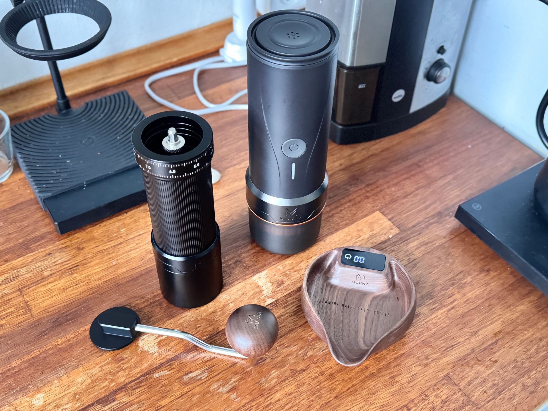 Black espresso maker and accessories in an open travel case on a wooden surface.