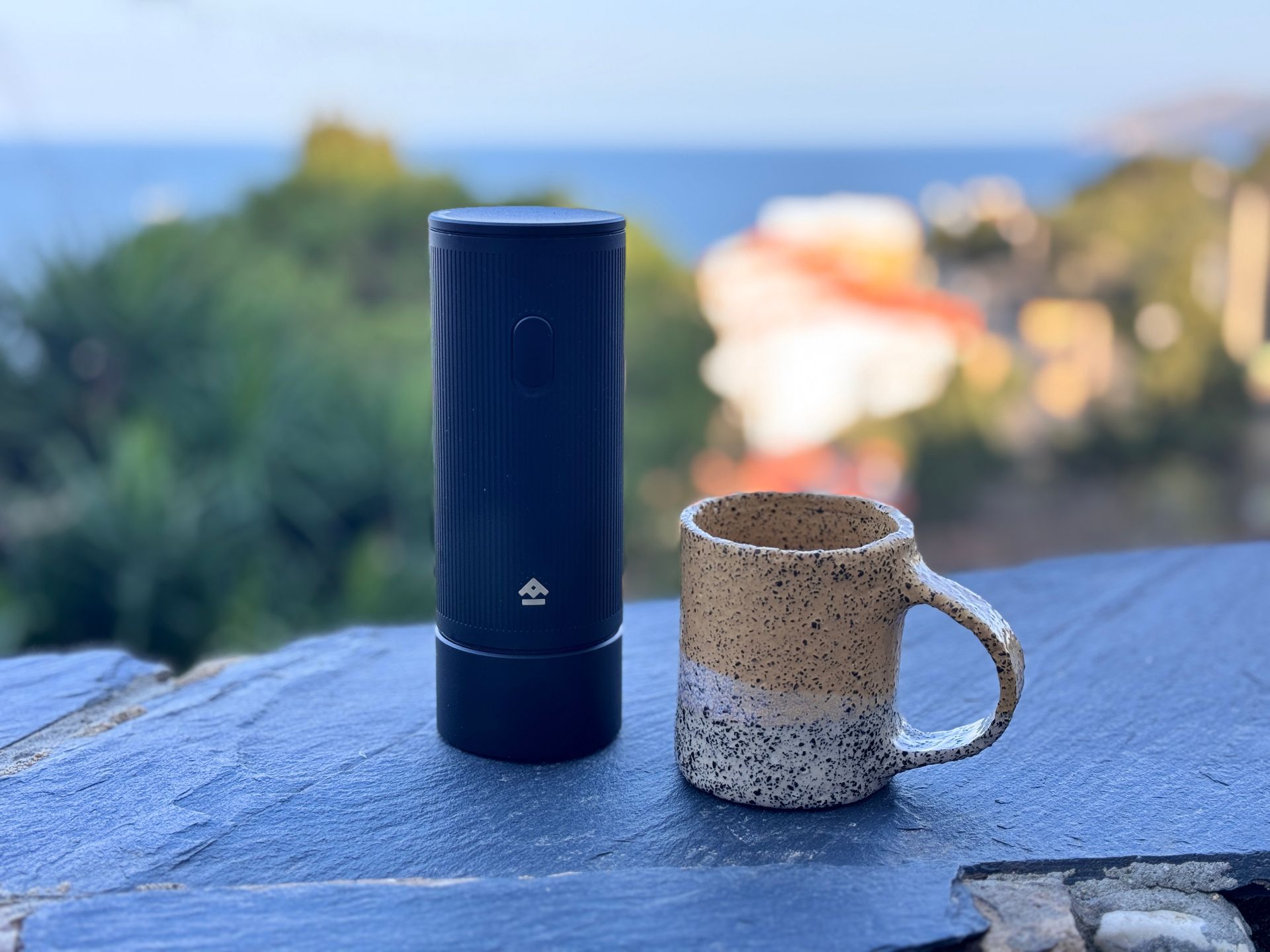 Black electric wine opener on a wood surface, with a lamp and decorative item in the background.