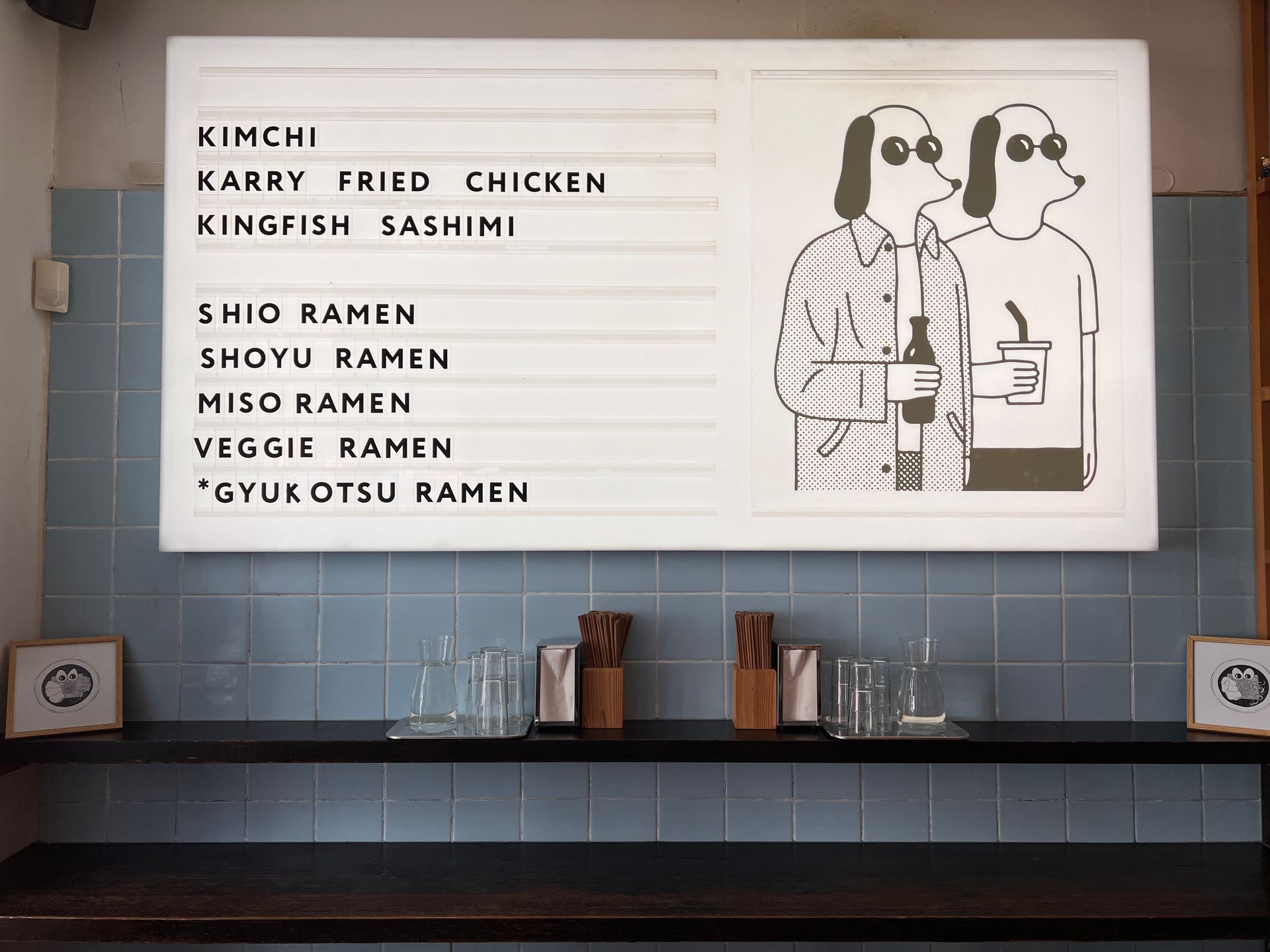 Menu board with food items and illustration of two dog-like characters.