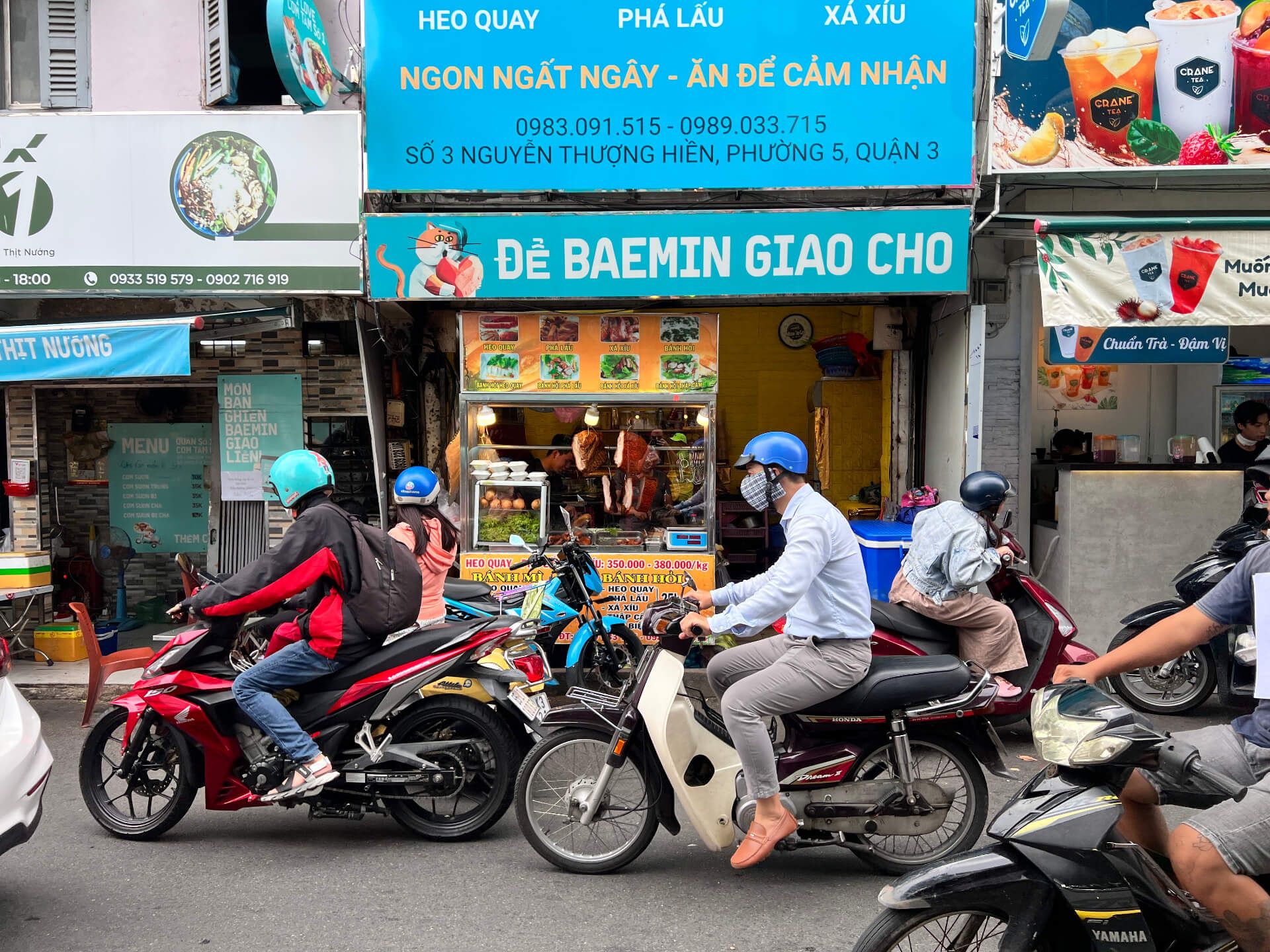 Motorbikes passing the Banh Mi stand in Ho Chi Minh City.