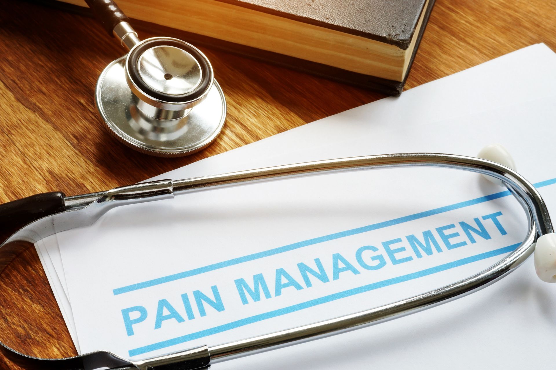 Pain management documents and stethoscope on book, symbolizing medical pain treatment.