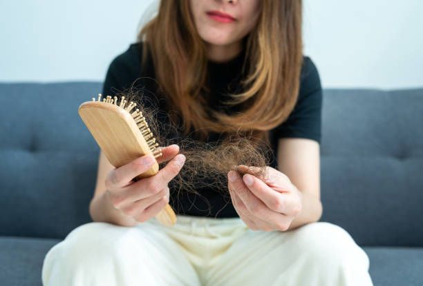 A woman is sitting on a couch holding a pack of pills.