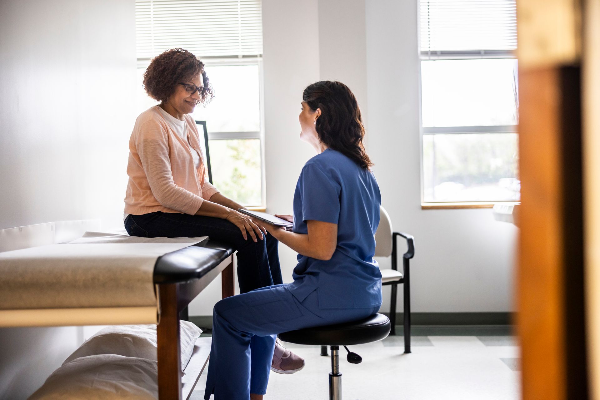 Doctor and senior woman discussing treatment in doctors office.
