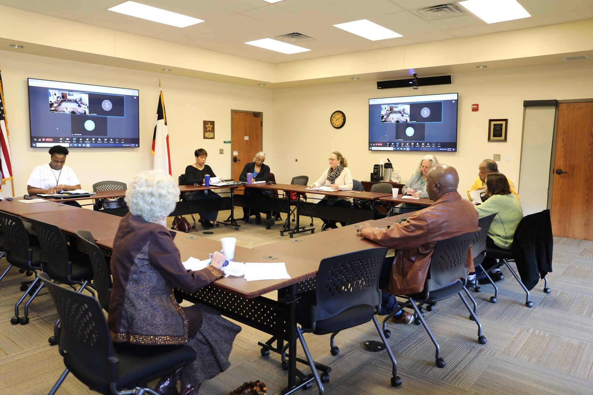 A group of people are sitting around a table in a conference room