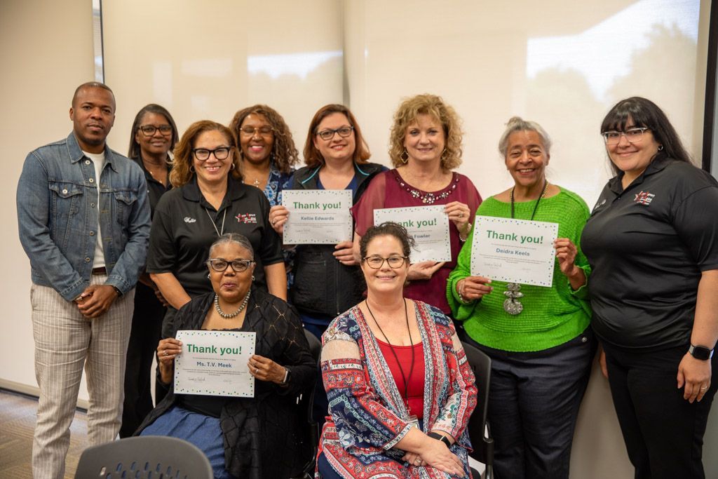 A group of AAA staff members is posing for a picture while volunteers are holding certificates