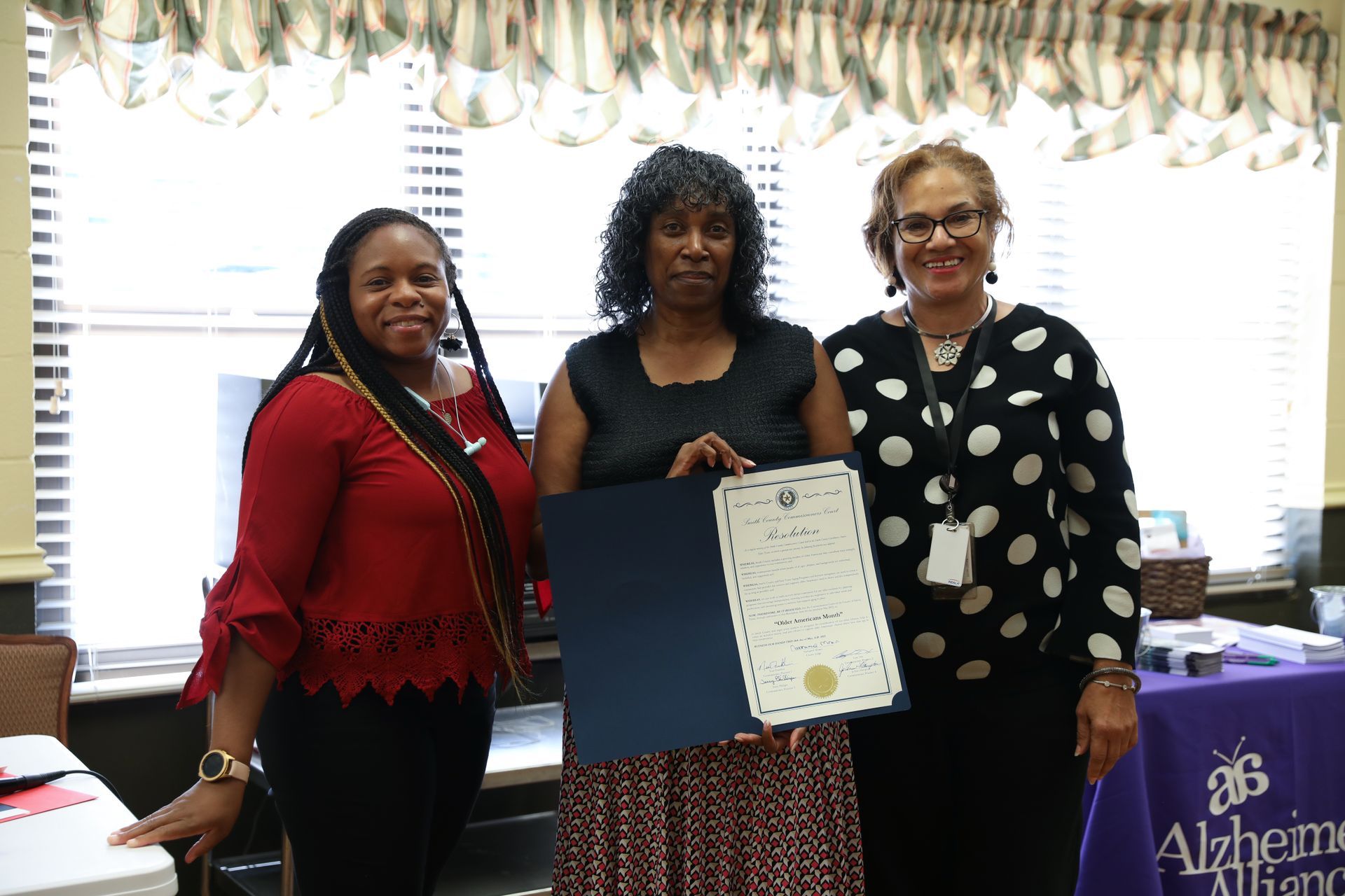 Three women are standing next to each other holding a certificate.