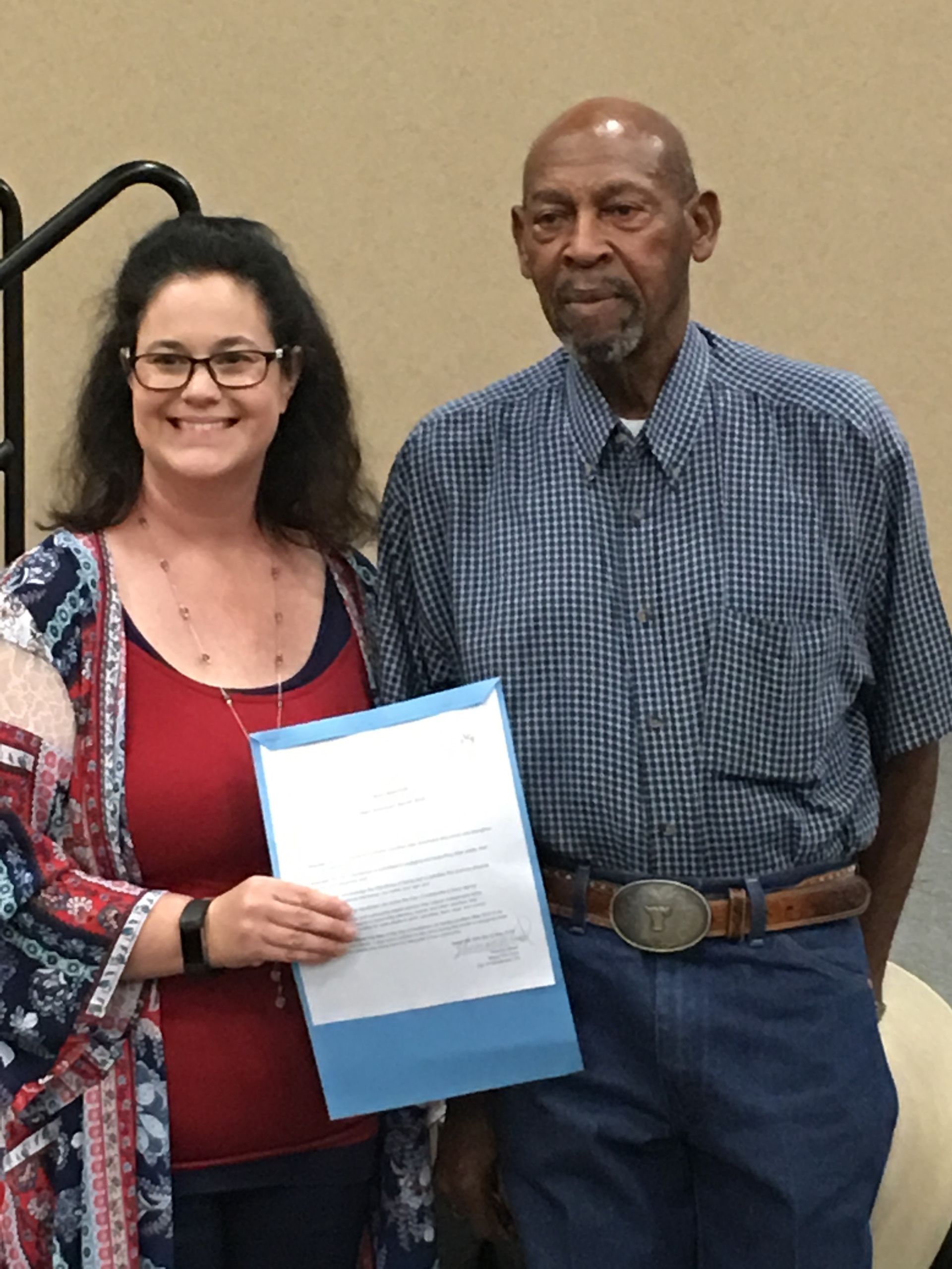 A man and a woman are standing next to each other and the woman is holding a piece of paper