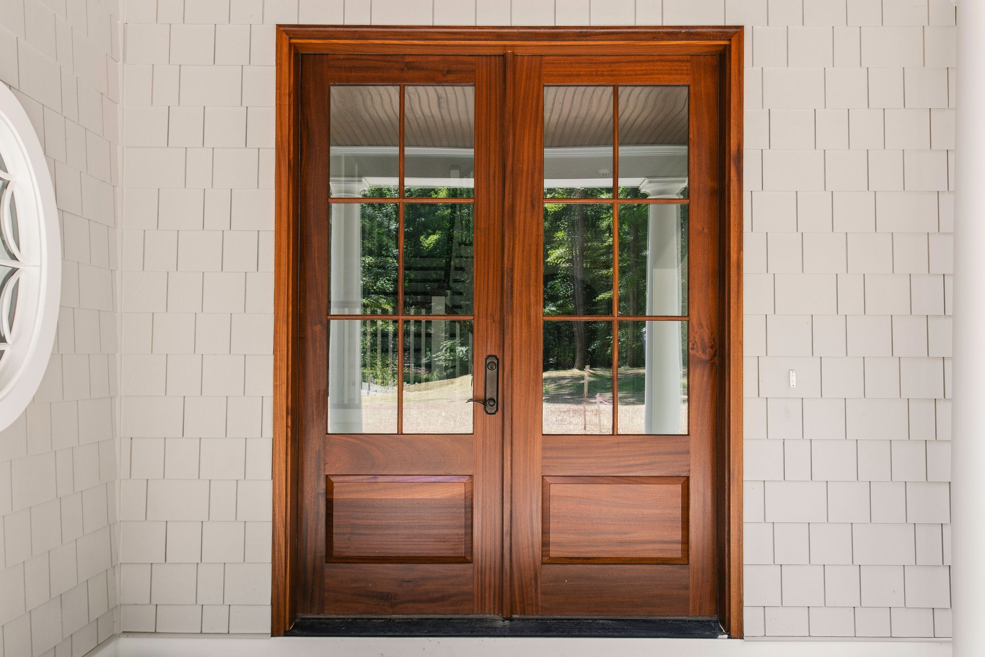 A pair of wooden doors on a white brick wall.