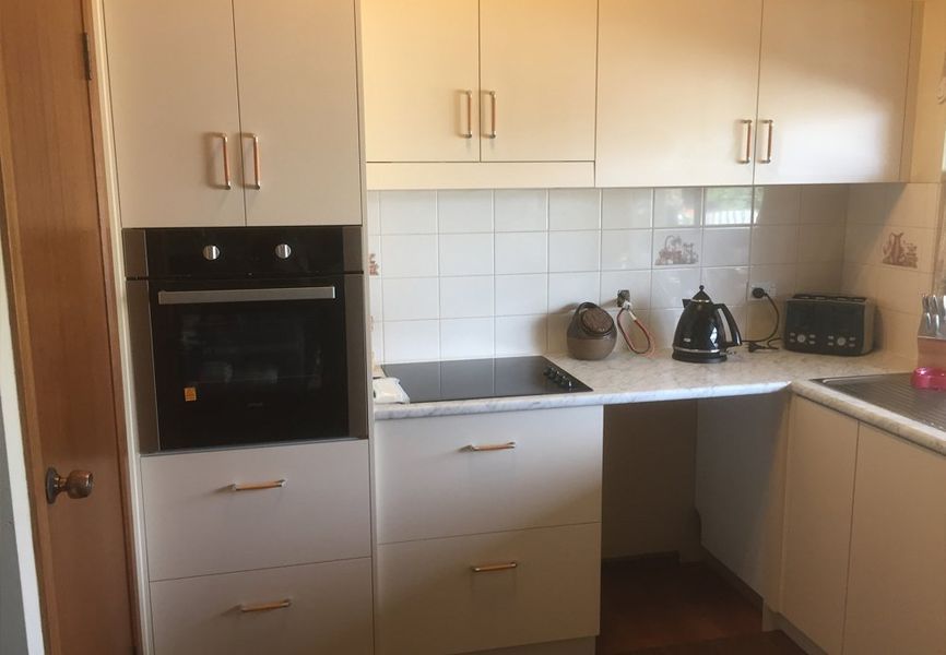 A kitchen with white cabinets , a black oven , a stove , and a sink.