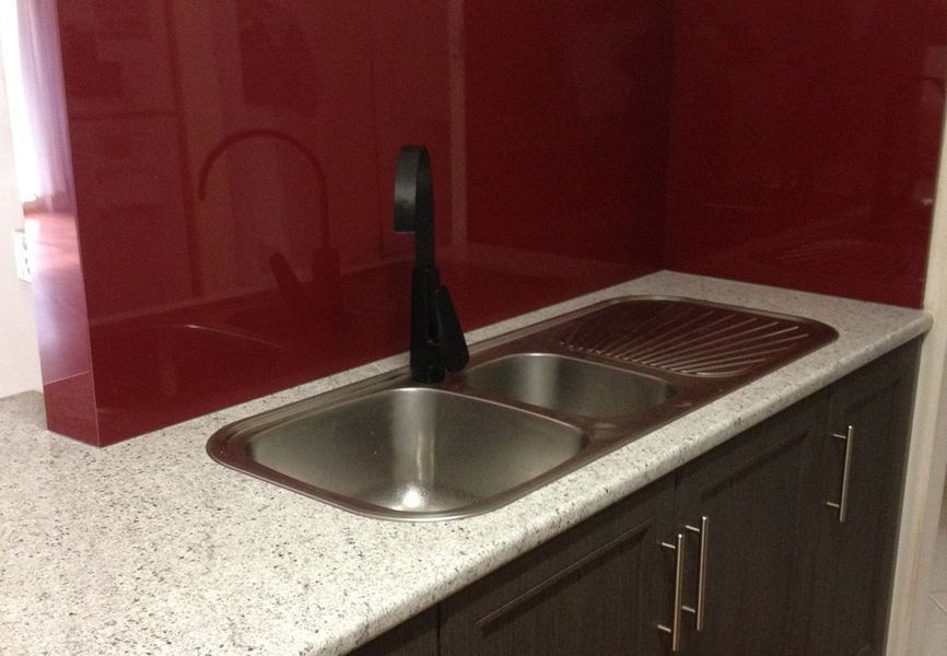 A kitchen sink with a red wall behind it