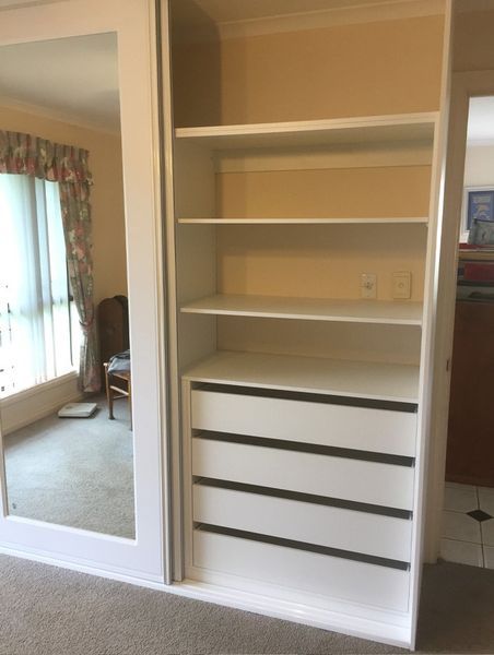 A closet with a mirror and shelves in a bedroom.