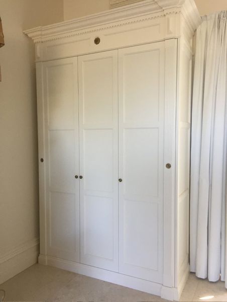 A white wardrobe in a room with white curtains