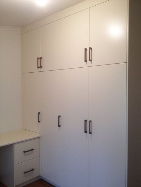 A room with lots of white cabinets and drawers