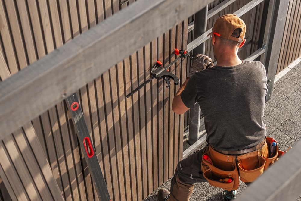 Woman in straw hat smiles, holding wine glass near a lake.