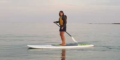 A guy on the stand up paddle board while on side view