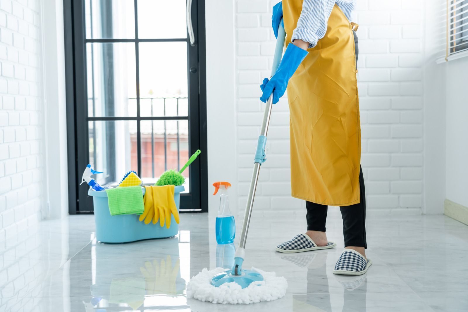 A woman is cleaning the floor with a mop.