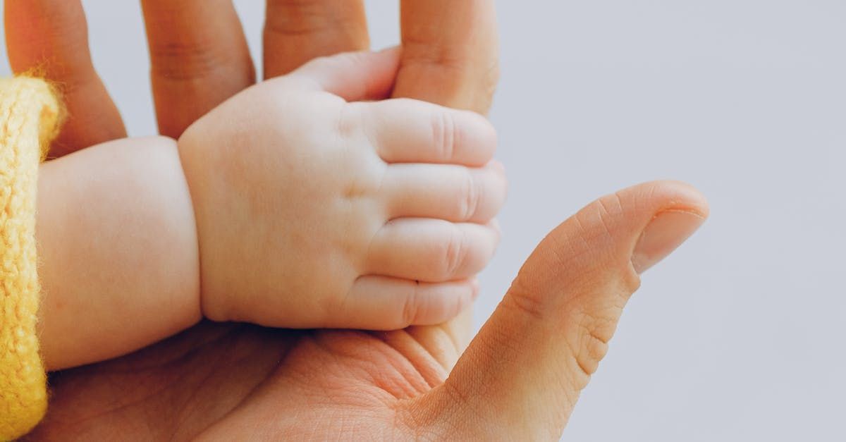 A person is holding a baby 's hand in their hand.