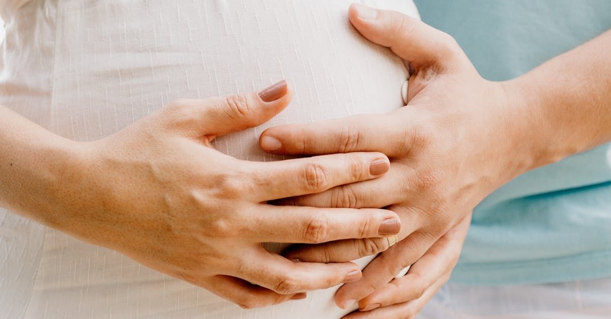 A pregnant woman is holding her belly with her hands.