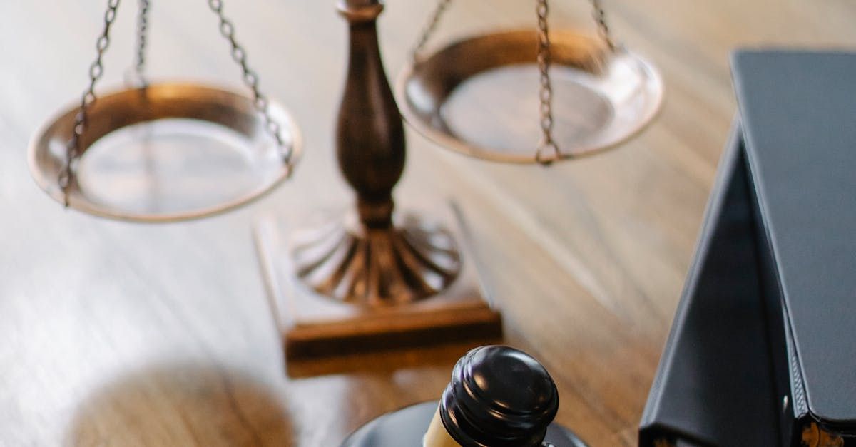 A bottle of wine is sitting on a wooden table next to a scale of justice.