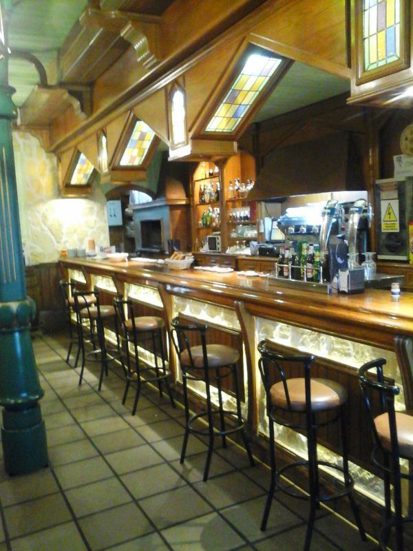 Una larga barra de madera con taburetes en un restaurante.